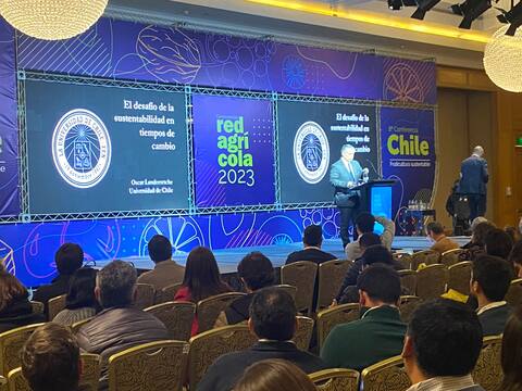 Conferencia académica con público en un salón de hotel