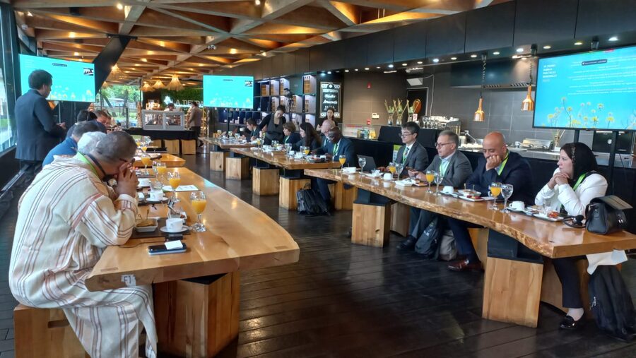 Delegados de varios países con credencial, reunidos en una mesa larga durante una sesión de trabajo de la Cumbre Mundial de las Regiones